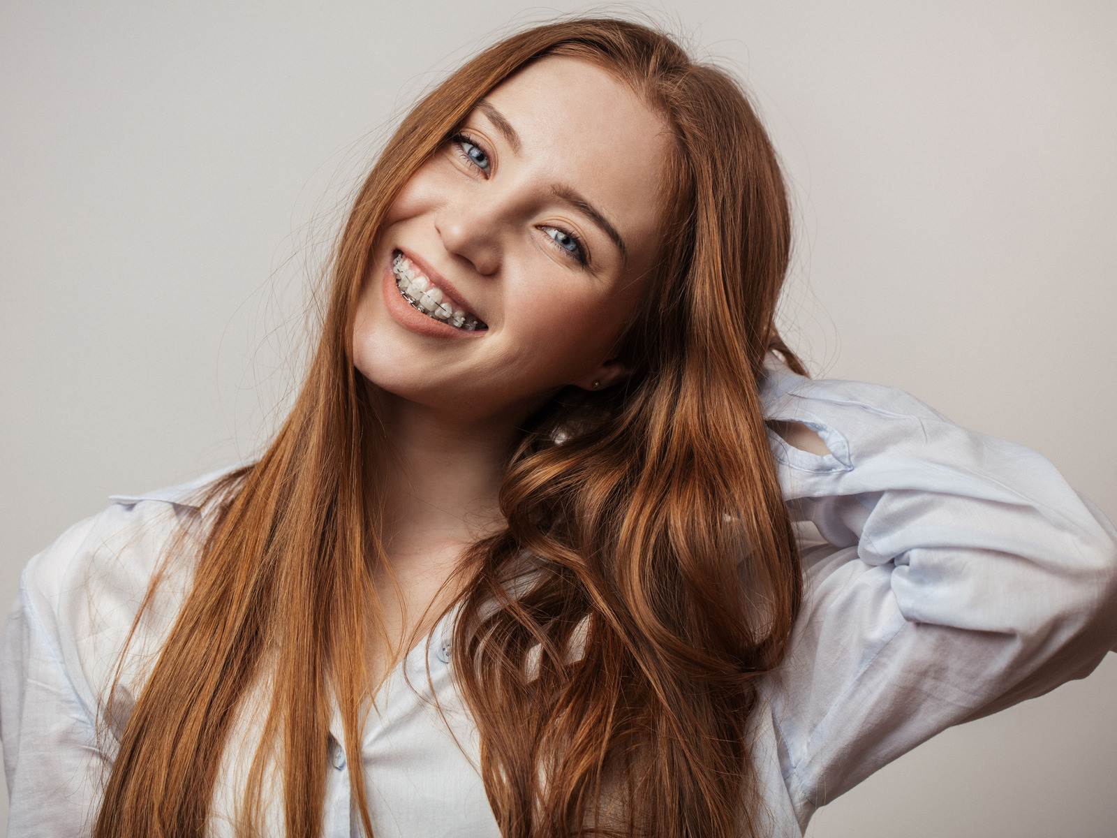 Happy young woman with red hair smiling in braces