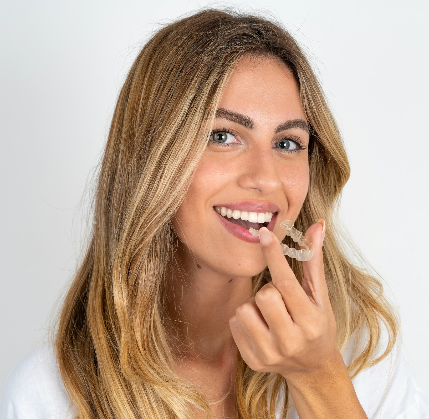 Young woman holding an invisible aligner confidently