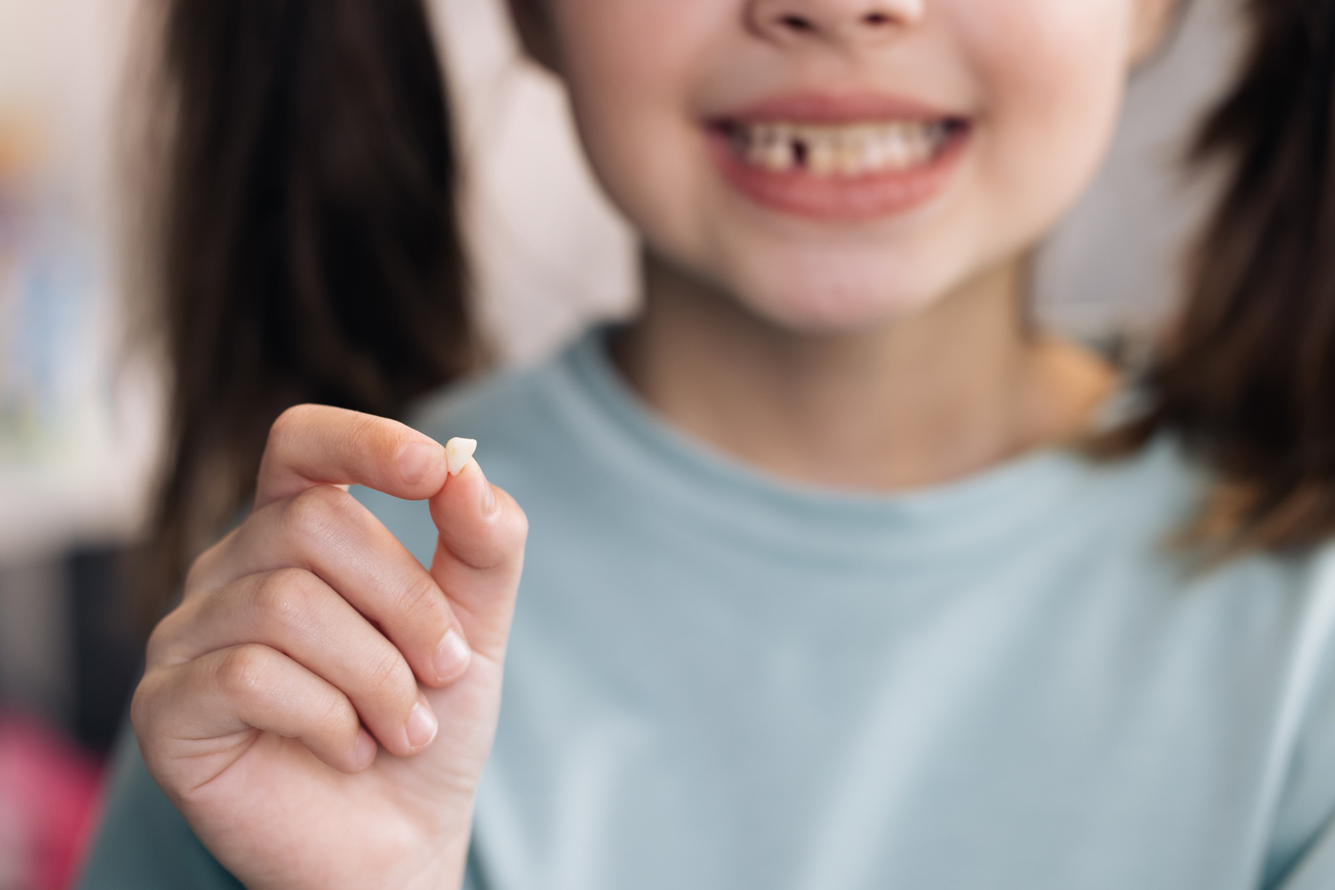 Happy girl holding her fallen baby tooth