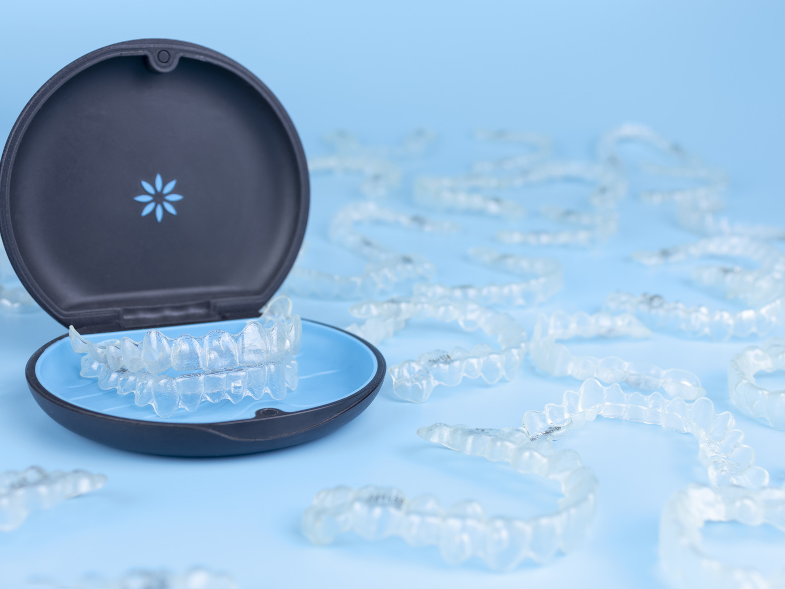 Black container for removable Invisalign aligners on blue background